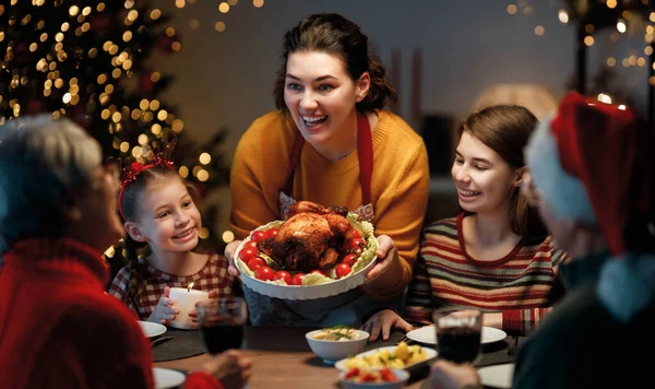 Mutlu Noeller! Mutlu aile evde yemek yiyor. Kutlama tatili ve ağacın yakınındaki birliktelik.