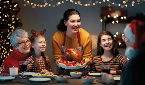 Mutlu Noeller! Mutlu aile evde yemek yiyor. Kutlama tatili ve ağacın yakınındaki birliktelik.