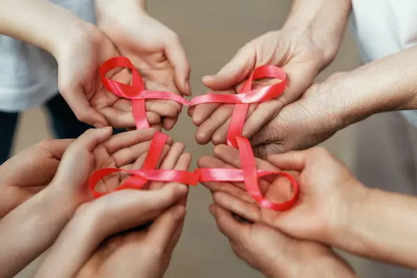 粉红缎带的妇女的手象征着疾病意识的概念 表达了对癌症患者和幸存者的声援和支持 不同世代的人 — 图库照片