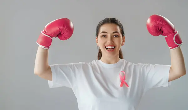 戴着粉色缎带的拳击手套的女人是战胜癌症的象征 提高对战胜肿瘤疾病的人的知识水平 — 图库照片