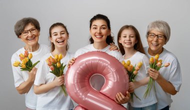 Mutlu kadınlar günü! Çocuklar annelerini ve büyükannelerini onlara çiçek veren laleleri kutluyor. Anneanneler, anne ve kızlar açık gri arka planda gülümsüyorlar. Aile tatili ve birliktelik.