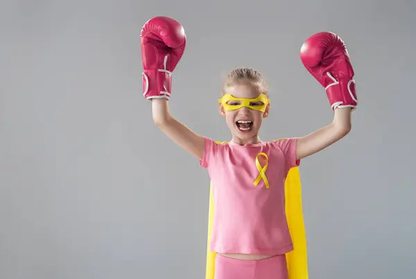 ガンとの戦いの象徴として黄色いリボンでボクシング手袋の子供 腫瘍疾患を克服した子供に関する知識のレベルを高める — ストック写真
