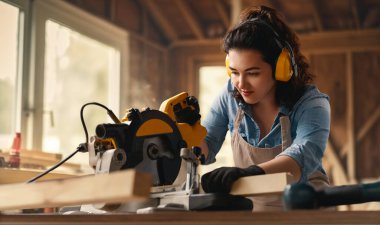 Genç kadın marangoz bir atölyede çalışıyor..