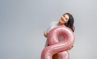 Gri duvar arkasında sekiz şeklinde balonu olan güzel genç bir kadın..