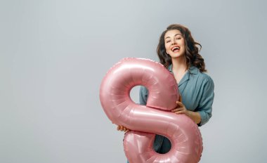 Gri duvar arkasında sekiz şeklinde balonu olan güzel genç bir kadın..