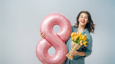 Sarı çiçekli güzel bir genç kadın ve gri duvar arkasında sekiz şeklinde bir balon..