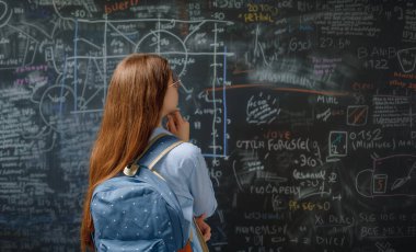 Okula dönelim. Mutlu şirin, çalışkan genç kapalı mekanda. Kız sınıfta tahtada öğreniyor.. 