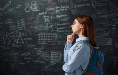 Okula dönelim. Mutlu şirin, çalışkan genç kapalı mekanda. Kız sınıfta tahtada öğreniyor.. 