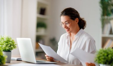 Ofiste dizüstü bilgisayarla çalışan mutlu, sıradan bir kadın..