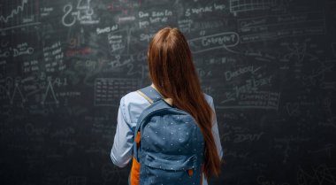 Okula dönelim. Mutlu şirin, çalışkan genç kapalı mekanda. Kız sınıfta tahtada öğreniyor.. 