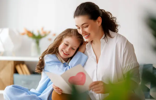 母亲节快乐 孩子的女儿正在向妈妈道贺 并给她寄明信片 妈妈和女孩笑着和拥抱 家庭假日和团聚 — 图库照片