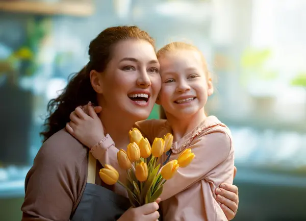 ハッピーマザーの日 子供の娘は母親を祝福し 花を与えています ママと少女は微笑み 抱きしめている 家族の休日とトータル — ストック写真