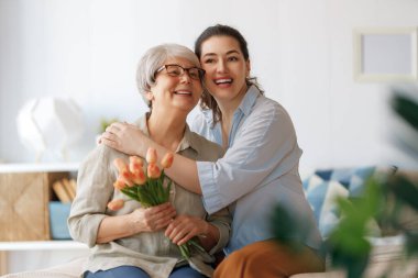 Güzel genç bir kadın ve elinde çiçeklerle annesi ellerinde laleler..  
