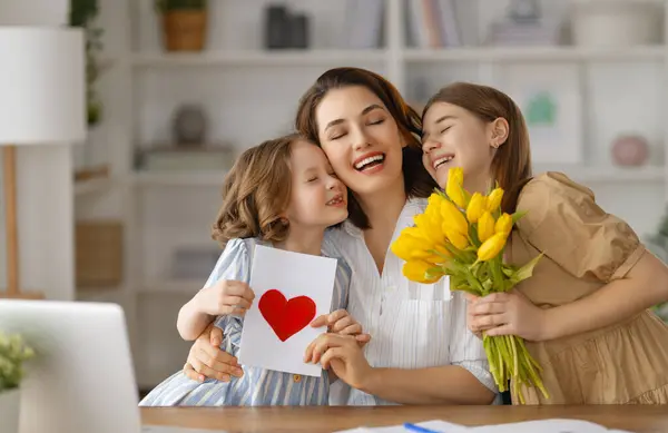 ハッピーマザーの日 子どもたちは母親を祝福し 花をあげている ママと女の子は微笑み 抱きしめている 家族の休日とトータル ストックフォト
