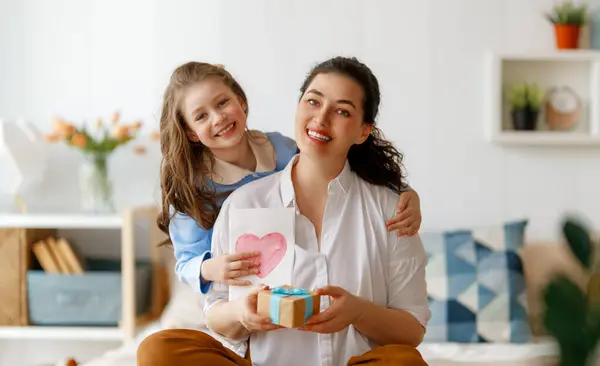 ハッピーマザーの日 子供の娘は母親を祝福し ポストカードを渡しています ママと少女は微笑み 抱きしめている 家族の休日とトータル ストック画像