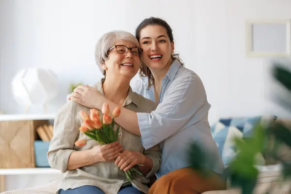 Mooie Jonge Vrouw Haar Moeder Met Bloemen Tulpen Handen Thuis Stockfoto