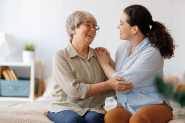 Güzel anne ve kız evde yatakta otururken konuşuyor ve gülümsüyor..