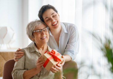 Güzel bir genç kadın annemi kutluyor ve ona hediye veriyor..  