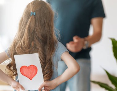 Çocuk kızı babasını tebrik ediyor ve ona kartpostal veriyor. Aile tatili ve birliktelik.