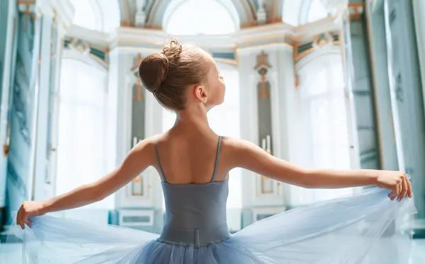 可爱的小女孩梦想成为一名芭蕾舞演员 孩子们穿着一件燕尾服在舞厅里跳舞 孩子在学芭蕾 图库照片