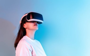 Metaverse teknoloji konsepti. Açık mavi duvar arka planında sanal gerçeklik gözlüklü kadın. Gelecekçi yaşam tarzı.