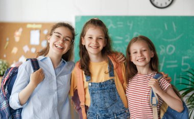 Okulun öğrencileri. Sınıfta sırt çantalı kızlar. Gençler kucaklaşıyor. Dersler başlıyor. Sonbaharın ilk günü. 