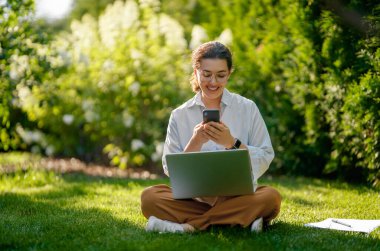 Mutlu kadın yaz sabahı dizüstü bilgisayarda çalışıyor bahçede oturuyor..