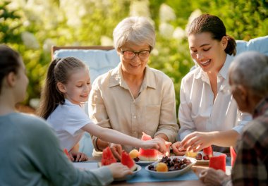 Happy family spending time together in summer morning. Family sitting in the garden and enjoying the conversation. clipart