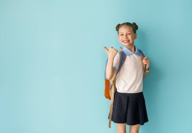 Açık mavi arka planda duran sevimli mutlu genç. Sırt çantalı çocuk, kız okula dönmeye hazır.. 
