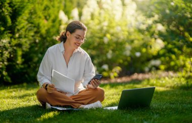 Mutlu kadın yaz sabahı dizüstü bilgisayarda çalışıyor bahçede oturuyor..