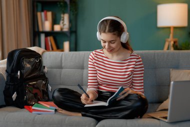 Mutlu çocuk kanepede oturuyor. Genç kız ödevini yapıyor..