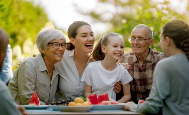 Mutlu aile yaz sabahları birlikte vakit geçirir. Aile bahçede oturuyor ve sohbetin tadını çıkarıyor..