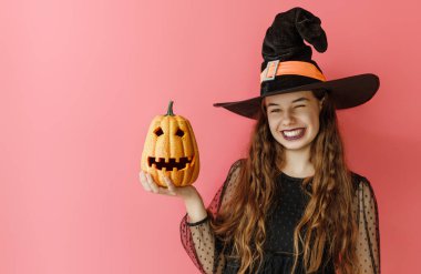 Cadılar Bayramı balkabağı giymiş, cadılar bayramı kostümlü, pembe duvarlı güzel kız..