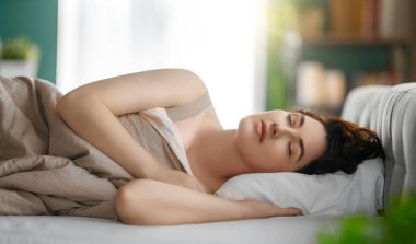 Güzel genç bir kadın evdeki yatak odasında uyuyor..