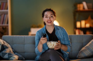 Televizyon izleyen genç bir kadın, akşamları patlamış mısırlı filmler. Kız evde vakit geçiriyor..