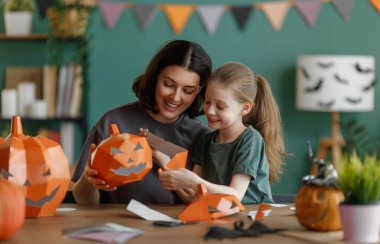 Mutlu aile Cadılar Bayramı için hazırlanıyor. Anne ve çocuk evde balkabağı kesiyorlar..