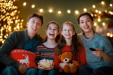 Mutlu Noeller ve mutlu yıllar. İnsanlar içeride ağaçların yanında eğleniyorlar. Evde tatil filmleri izlemeyi seven bir aile. Anne, baba ve kızları birlikte vakit geçiriyorlar..