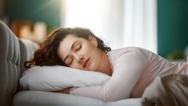 A beautiful young woman is sleeping in the bedroom at home.