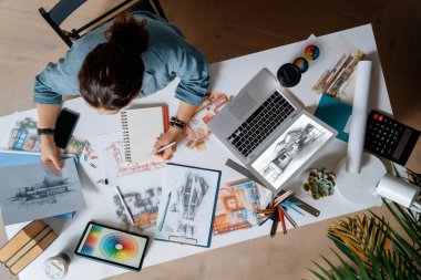 Stüdyoda çalışan dizüstü bilgisayar ve çizimler kullanan tasarımcı.