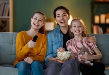Mutlu aile projektörü, TV, akşam evde patlamış mısırlı filmler. Anne ve kızları birlikte vakit geçiriyorlar..