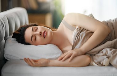 Güzel genç bir kadın evdeki yatak odasında uyuyor..