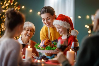 Mutlu noeller. Mutlu aile evde yemek yiyor. Kutlama tatili ve ağacın yakınındaki birliktelik.