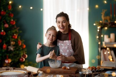 Mutlu Noeller ve mutlu tatiller. Aile hazırlığı bayram yemeği. Anne ve kızı kurabiye pişiriyor..