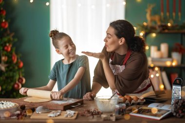 Mutlu Noeller ve mutlu tatiller. Aile hazırlığı bayram yemeği. Anne ve kızı kurabiye pişiriyor..