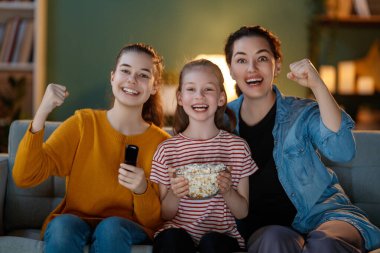 Mutlu aile projektörü, TV, akşam evde patlamış mısırlı filmler. Anne ve kızları birlikte vakit geçiriyorlar..