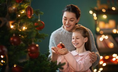 Mutlu Noeller, mutlu tatiller. Anne ve kızı kapalı alanda ağacın yanında. Noel 'den önceki sabah. 