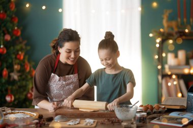 Mutlu Noeller ve mutlu tatiller. Aile hazırlığı bayram yemeği. Anne ve kızı kurabiye pişiriyor..
