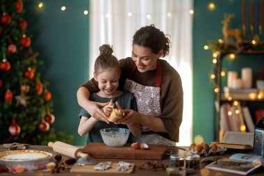 Mutlu Noeller ve mutlu tatiller. Aile hazırlığı bayram yemeği. Anne ve kızı kurabiye pişiriyor..