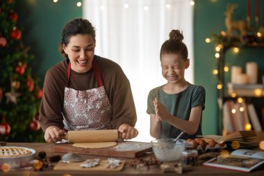 Mutlu Noeller ve mutlu tatiller. Aile hazırlığı bayram yemeği. Anne ve kızı kurabiye pişiriyor..