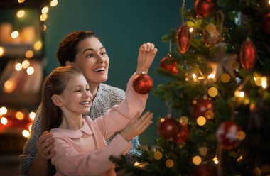 Mutlu Noeller, mutlu tatiller. Anne ve kızı kapalı alanda ağacın yanında. Noel 'den önceki sabah. 